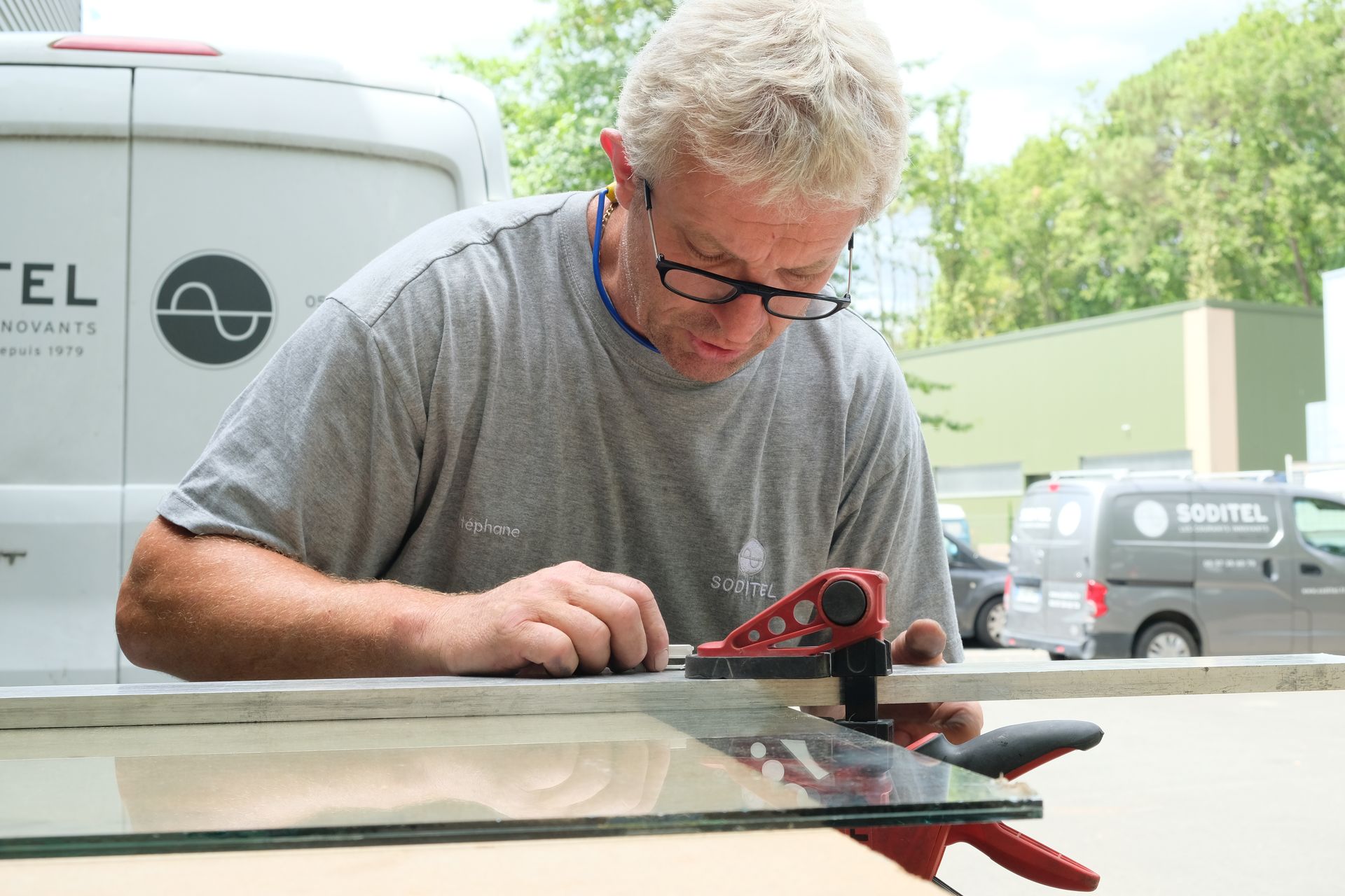 un technicien qui coupe du verre pour le changer sur une porte de hall