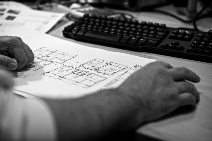 photo noir et blanc avec des mains et le plan d'un bâtiment